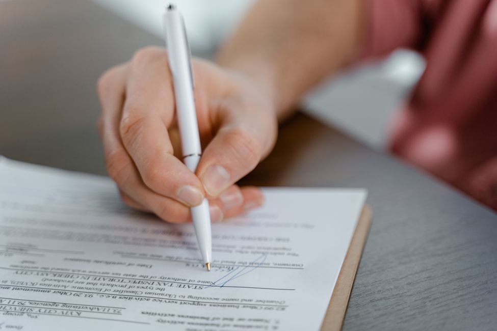 Close-up of a hand signing a contract with a pen